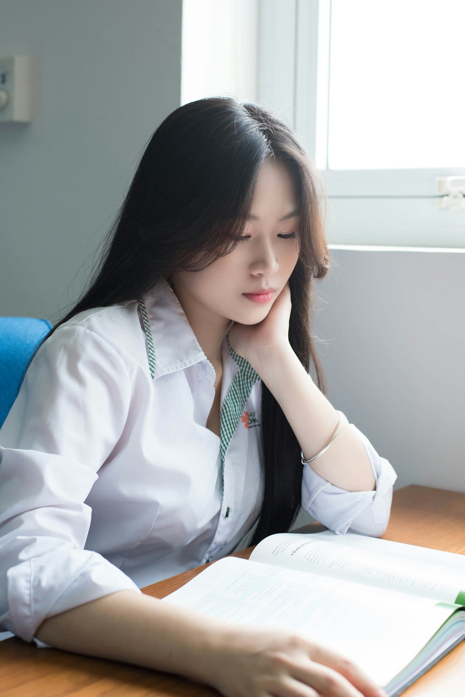 교복 차림의 학생이 혼자 책상에서 책을 보며 공부하는 모습