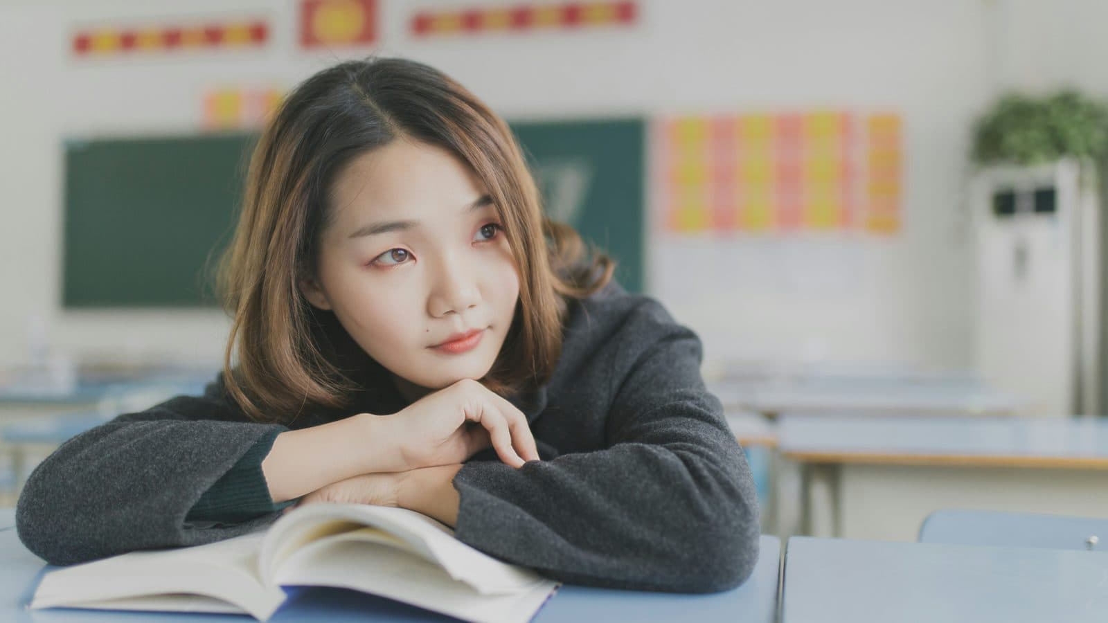 교실 책상에서 책을 펼쳐두고 영어 내신을 생각하며 공부하는 학생